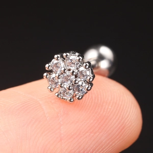 Macro shot of silver zircon flower stud earring held on fingertip with black background
