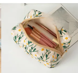 Detail of canvas toiletry bag featuring daisy embroidery and large storage capacity