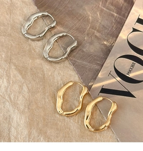 Close-up of gold and silver irregular geometric hoop earrings with liquid metal texture
