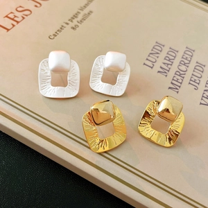 Detail view of hollow square geometric earrings in matte silver and polished gold finishes