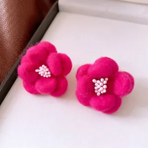 Elegant rose red wool floral stud earrings with white bead center on a white box