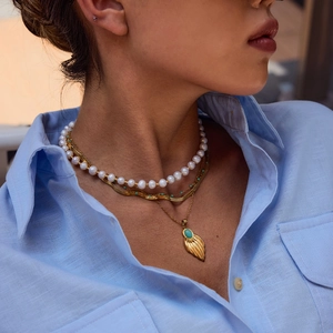 Layered necklace set with gold leaf turquoise pendant and pearl choker on model
