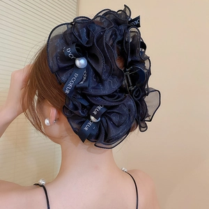 Détail d'une grande pince à cheveux noire avec perles et ruban en organza porté
