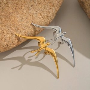 Minimalist gold and silver swallow rings displayed on a natural rock with a sleek finish