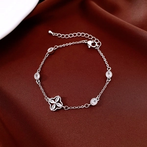 Macro detail of gold-plated clover bracelet with marquise zircon on red satin
