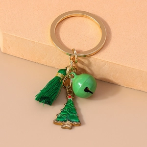 Close-up of golden Christmas keychain featuring a green tassel, bell, and tree charm