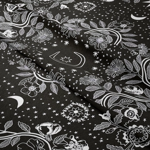 Close-up of black bohemian tapestry featuring white mandala moon and floral prints