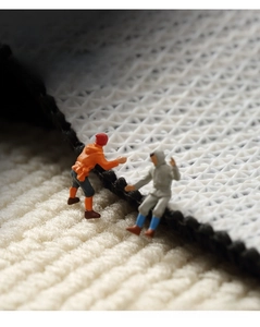 Macro detail of thick plush beige carpet with anti-slip diamond grid rubber backing