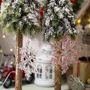 Detail of transparent and pink acrylic snowflake ornaments hanging on a Christmas tree