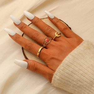Detail of bohemian gold stackable rings featuring sun and moon charms with a red stone
