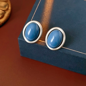 Close-up of vintage oval silver earrings with blue stones on a dark blue jewelry box
