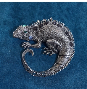 Detailed view of chameleon brooch with vintage silver finish and inlaid gemstones