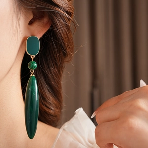 Close-up of vintage malachite drop earrings with golden accents on a professional model