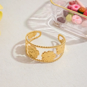 Close-up of 18K gold plated hollow floral pattern open cuff bracelet on textured surface