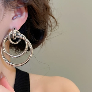 Détail de boucles d'oreilles anneaux argentés multicouches au fini métal poli