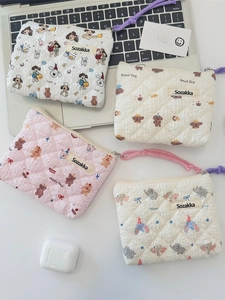 Quilted floral coin pouches with cute cartoon dog and bear patterns on a desk