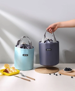 Detail of insulated cylindrical lunch bags with drawstring closure and grey carry handles