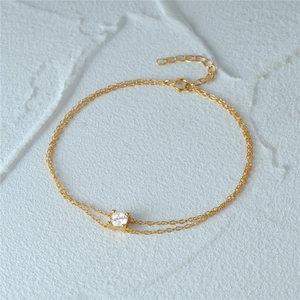 Macro view of a gold double-layer silver bracelet with a single round zircon stone