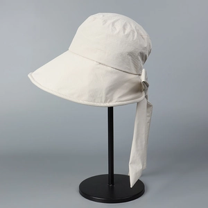 Detail of beige sun hat with wide brim and long decorative ribbon bow on a display stand