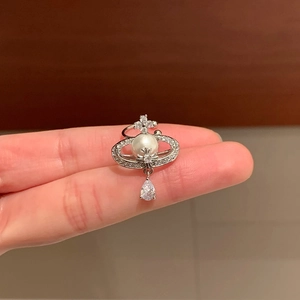 Detail of silver Saturn ear clip with pearl center, cubic zirconia and water drop pendant