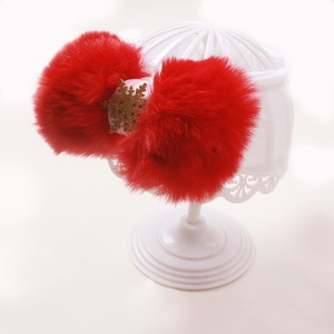Detailed shot of baby headband featuring red faux fur pom poms with golden snowflakes