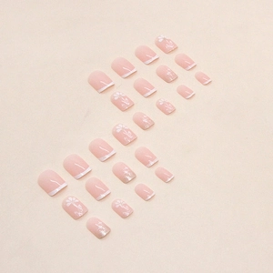 Pink nude press-on nails with white French tips and delicate floral patterns