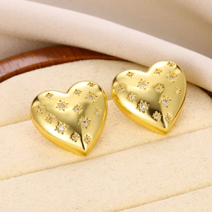 Macro shot of gold heart studs with starry zircon accents in a premium beige jewelry box