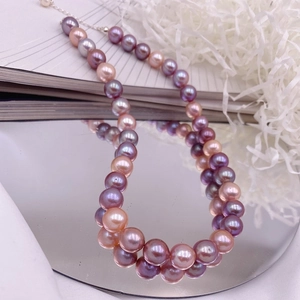 Detailed close-up of large baroque Edison pearls in pink and purple on a mirror