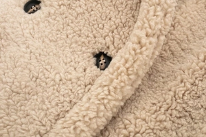 Detail of beige sherpa fleece texture and vintage brown buttons on oversized coat