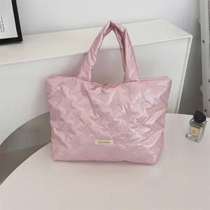 Detail of pink quilted handbag with bow pattern texture and branding label