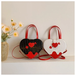 Close-up of heart-shaped crossbody bags in black and white crocodile texture