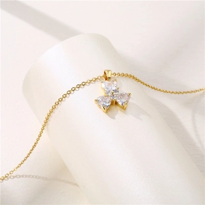 Collana dorata con ciondolo a trifoglio con tre cuori scintillanti su base bianca