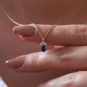 Collana in oro minimalista con un ciondolo a goccia blu reale e tre piccoli diamanti