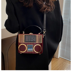 Detail of burgundy acrylic radio bag with glossy finish and gold metal hardware accents
