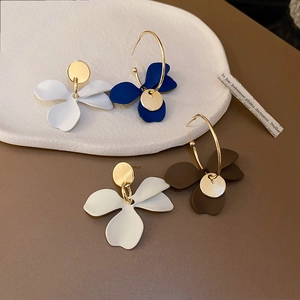 Vue détaillée des boucles d'oreilles fleurs en blanc, bleu et marron mat