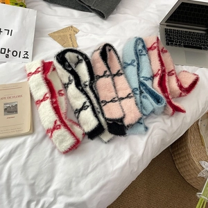 Various plush bow scarves in five colorways laid out in a cozy home setting decor
