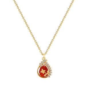 Luxurious gold necklace with red teardrop pendant and crystal halo on white background
