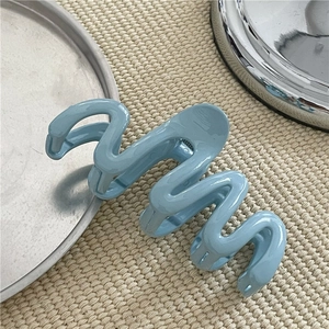 Close-up of light blue wave hair claw clip on beige woven fabric background