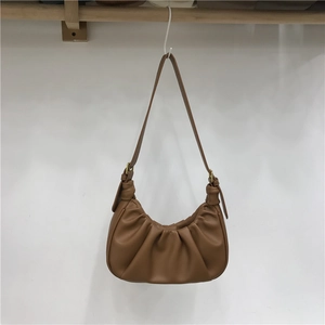 Detail of caramel pleated cloud bag with soft texture and adjustable shoulder strap