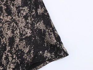 Detailed close-up of black fabric featuring textured gold metallic foil pattern