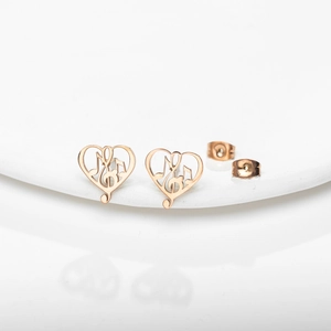 Rose gold heart musical note earrings with treble clef design on a white podium
