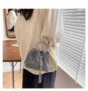 Chic black bucket bag with silver rhinestones and metal ring handle worn by a model