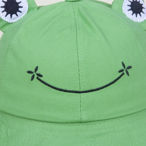 Green frog bucket hat with embroidered smiley face and cotton fabric detail