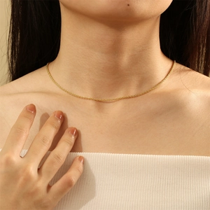Close-up of a gold minimalist thin cable chain necklace worn by a model on the neck