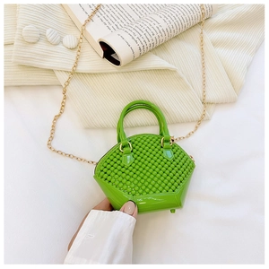Close-up of green mini jelly pearl shell bag with gold chain strap held by a model