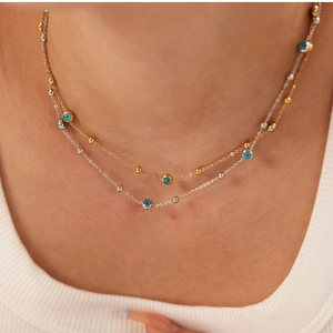 Close-up of double layer necklace with gold and silver chains featuring blue evil eye beads