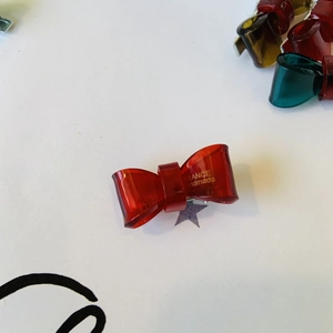 Dettaglio del fermaglio a fiocco rosso trasparente con scritta France Handmade oro