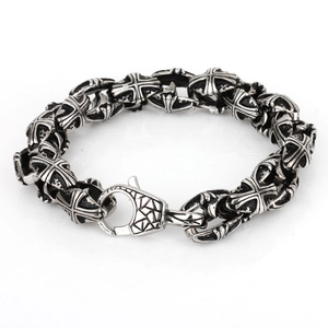 Gothic style silver-black cross steel bracelet with large lobster clasp on white surface