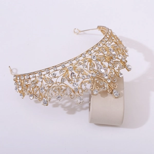Detailed close-up of golden bridal tiara with sparkling crystals on a beige stand