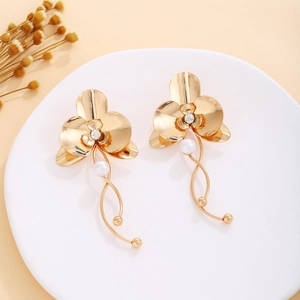 Detailed view of gold flower earrings with pearls and rhinestones on a white ceramic tray
